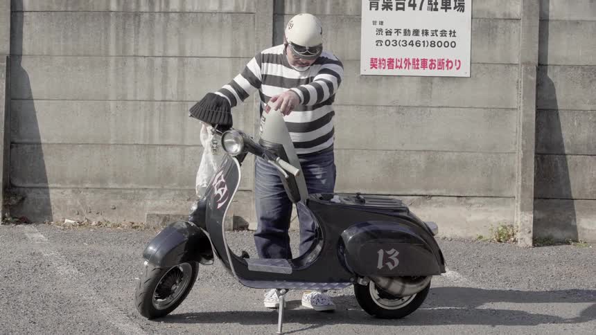 Heavyset man looking under the seat of his scooter in a city