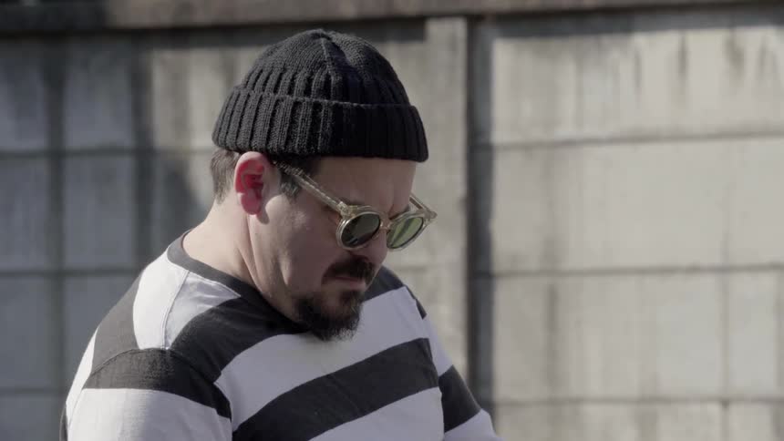 A man wearing a striped shirt talks on his phone