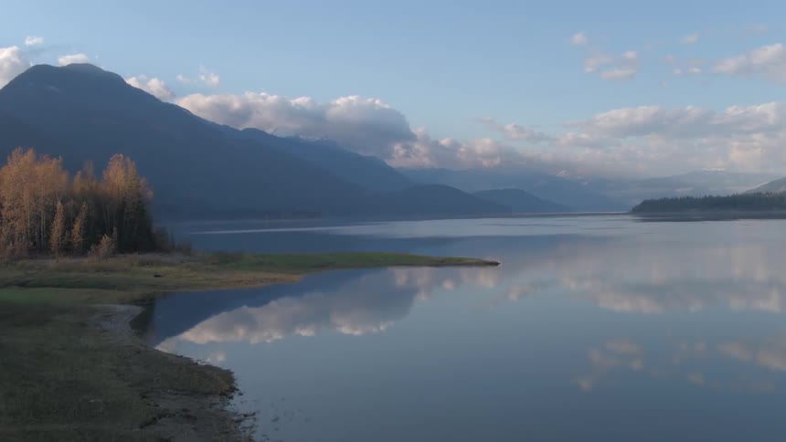 A mountain lake reflects blue sky and clouds on a sunny day