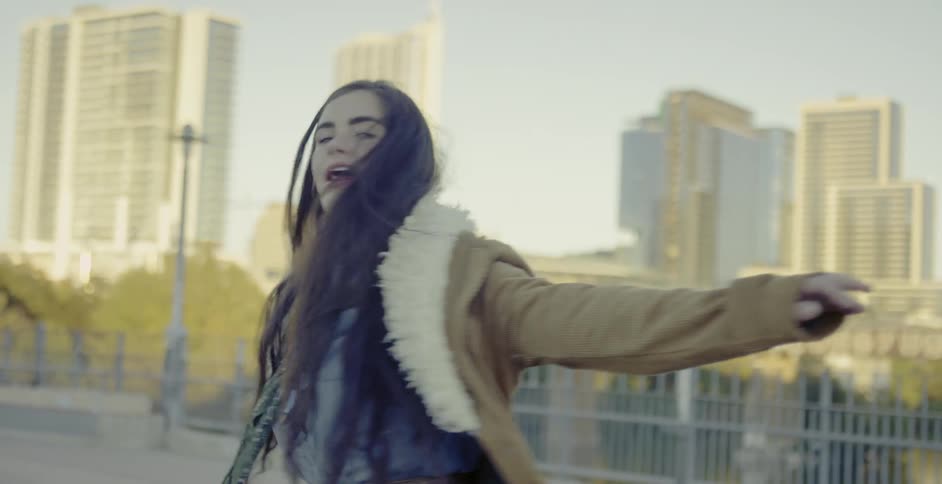 Woman twirls around in the city during the day
