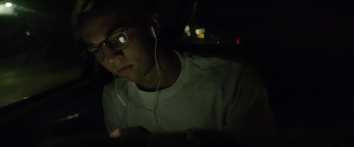 A man listens to headphones in a moving car