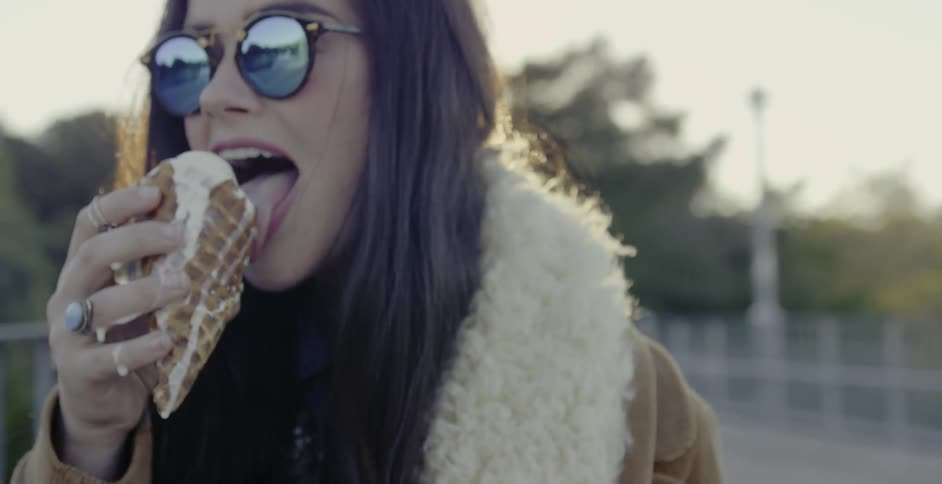 A woman eats a melting ice cream cone