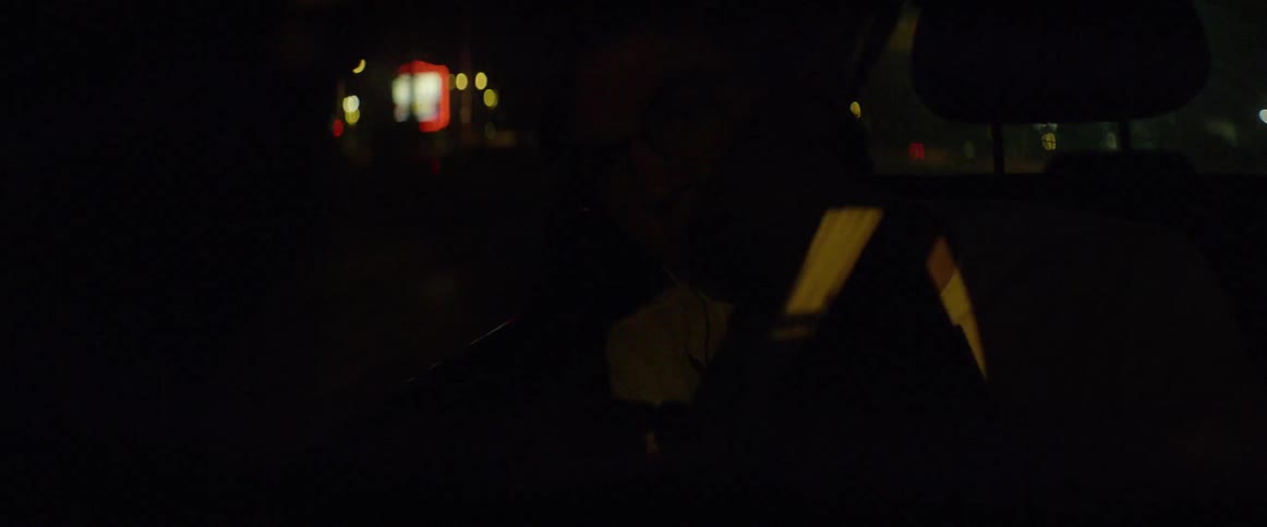 A man writes in his notebook as he rides in a car
