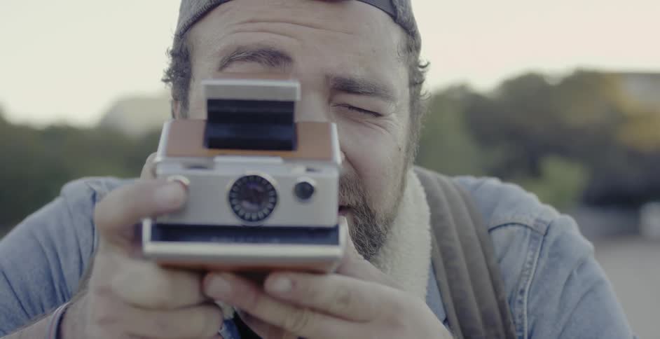 A man taking a photograph with a polaroid camera