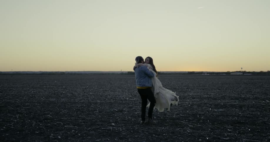 Man and woman hug and turn in an empty field of dirt