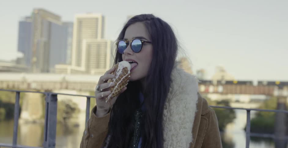A woman licks a melting ice cream cone