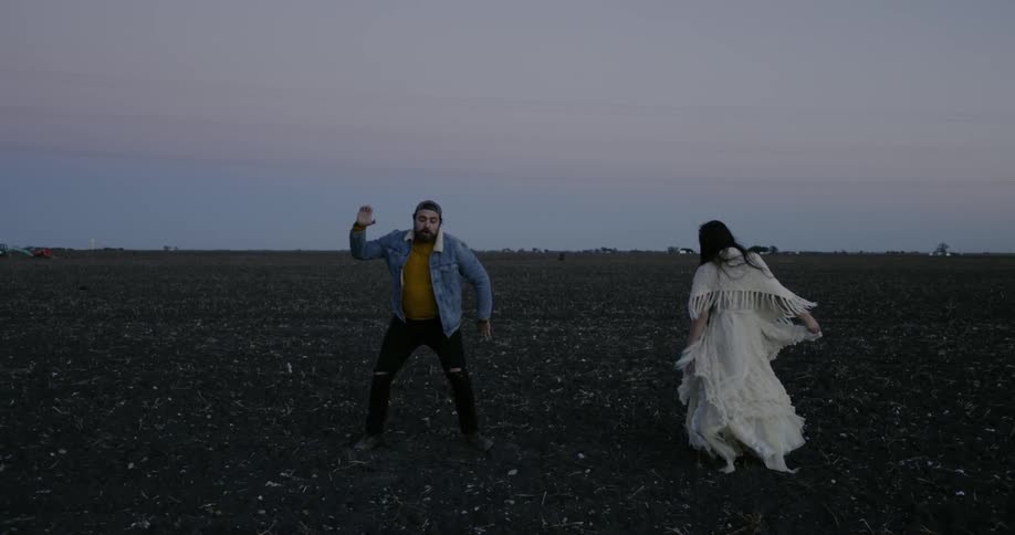 Man and woman dance in a dirt field