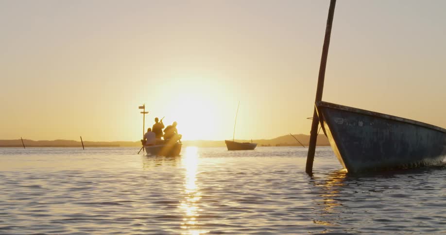 People are paddling a boat at sunrise