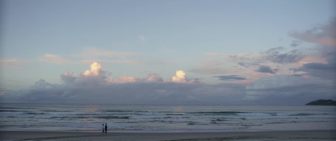 People walking across a beach on a cloudy day