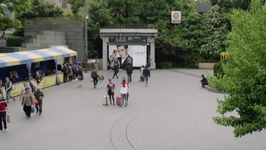 Tourists and pedestrians are walking through a plaza in an asian city in daylight