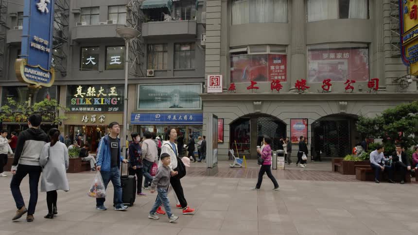 A family walks through a plaza in an asian city in daylight