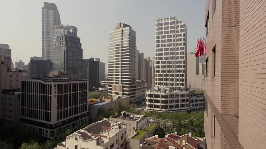 Flags flutter in the breeze off the side of a high rise in a city in daylight