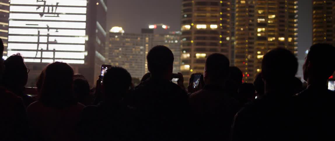 Group of people stand photographing building at night
