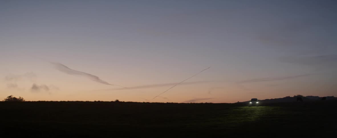 A car is driving and flashing its light at dawn