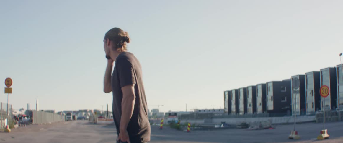 A man stands alone on an empty road holding a smartphone to ear.