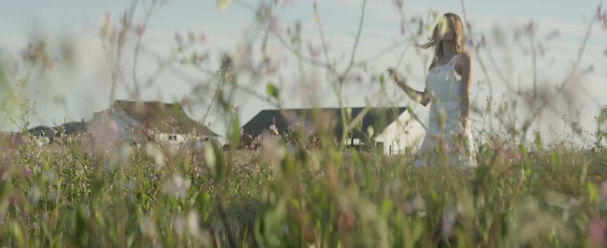 A woman is walking in a field with flowers in daylight