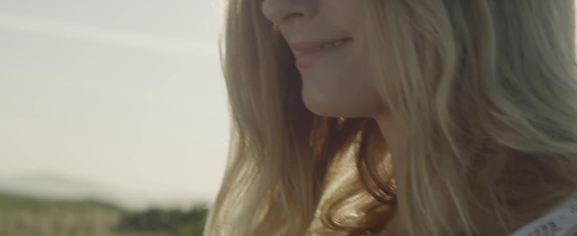 A woman standing outside in the sunlight is turning her head