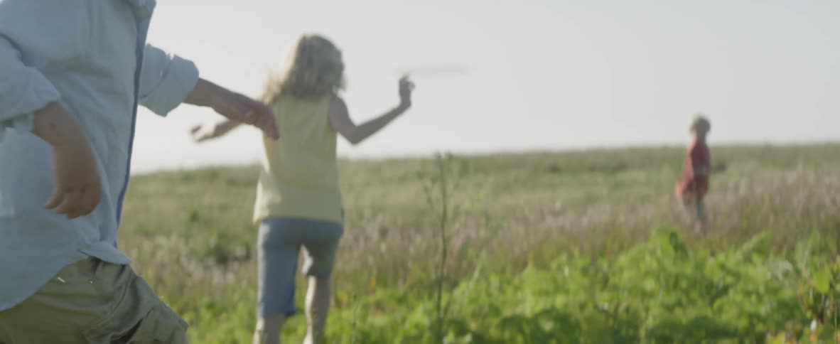 Children run in the grass together on a cloudy day