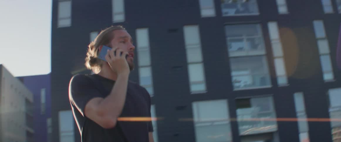 The man walks across street talking on his phone