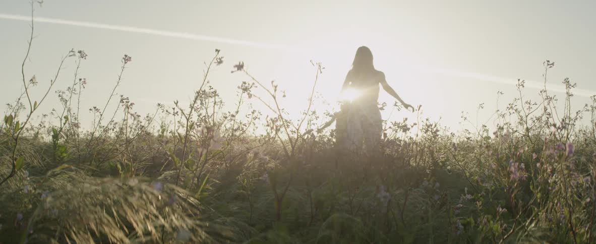 A woman and girl frolic in a grassy field on a sunny day