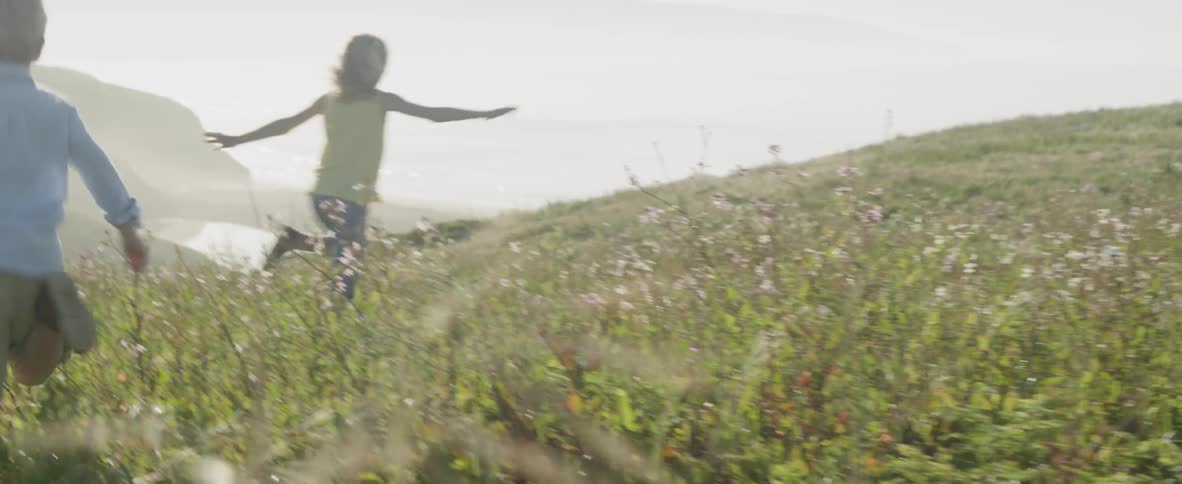The children run and jump through the grass and flowers