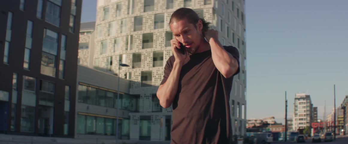 A man talking on his phone in the street is pacing