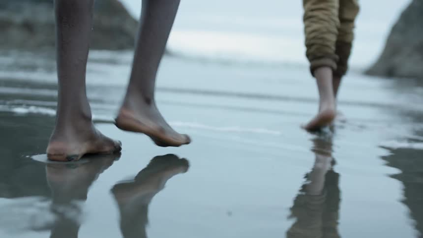 Two people walk in the water on the beach