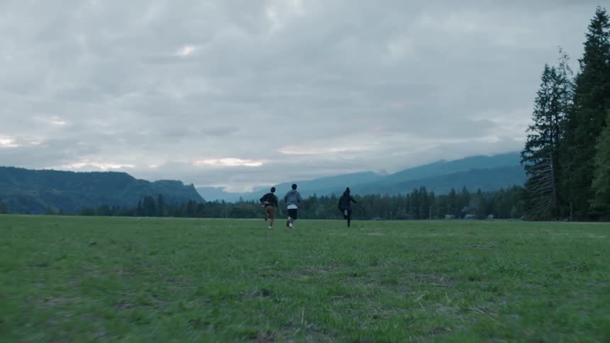 Teenagers run across a rural field