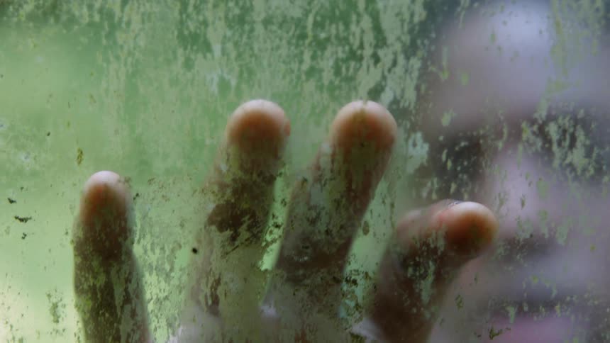 Person touches a window with green slime on it