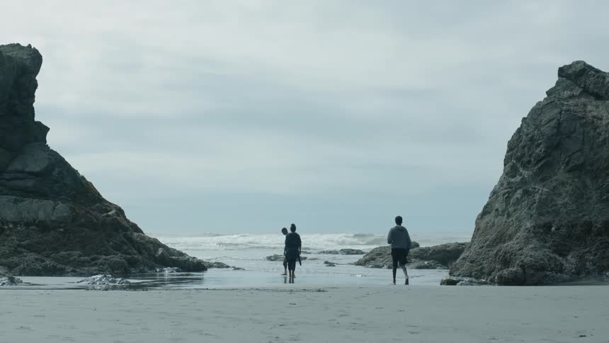 Kids stand by rocks on the shore