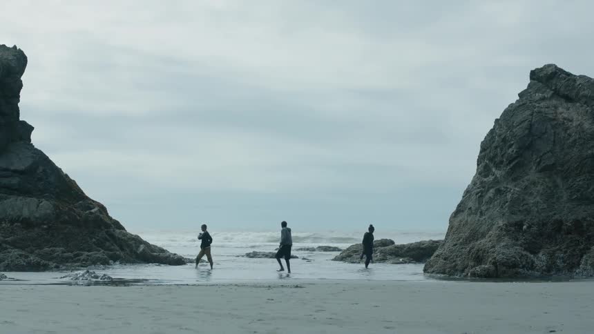 Three people walk on the beach shore