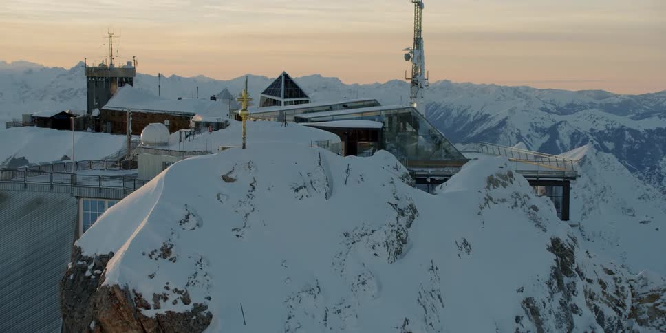 A building sits on top of a snow covered mountain ridge