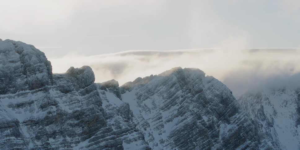 The tall ice covered mountain has clouds on top