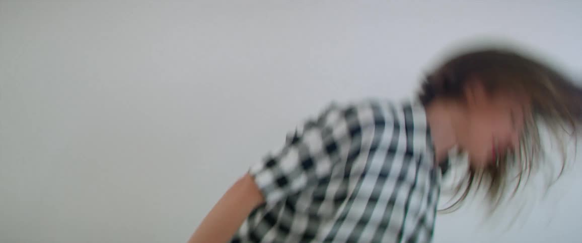 Young happy woman dances and flips hair around in white studio