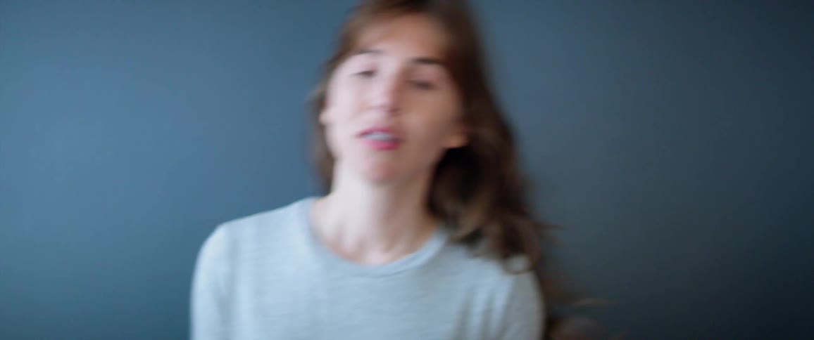 Woman dancing in front of a plain blue background