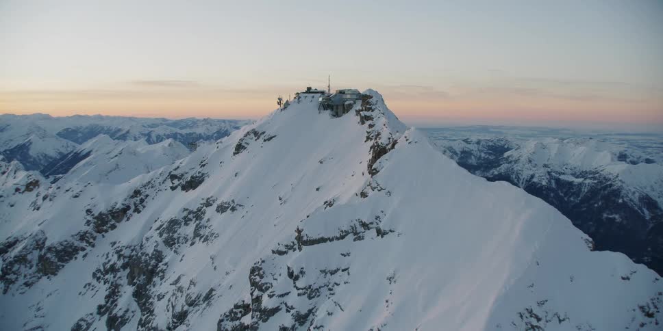 An observatory sits on a snow covered mountain ridge