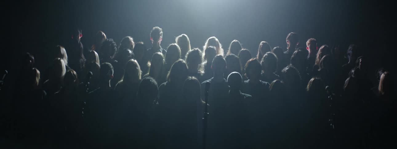 Group of people stand on a dark stage