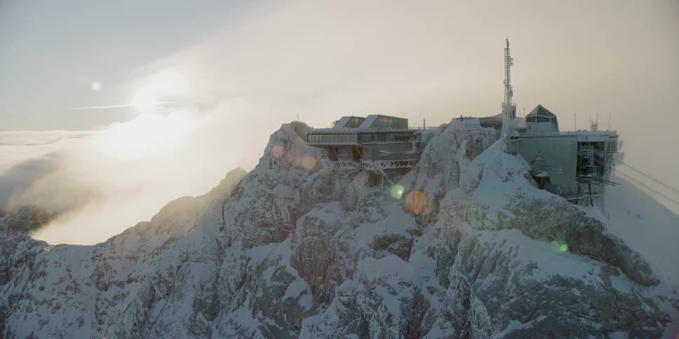The building sits on the tall mountain surrounded by clouds