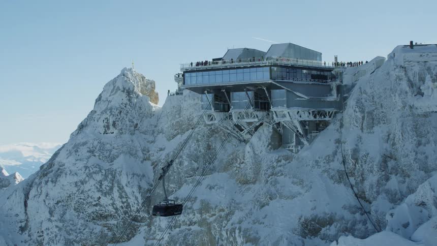 A ski lift carries up towards a building atop a mountain