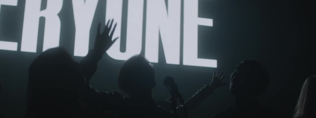 People cheer and wave on the dark stage