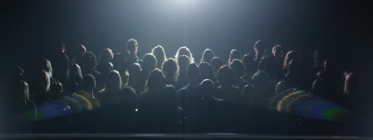 The large crowd is standing in front of a flashing screen