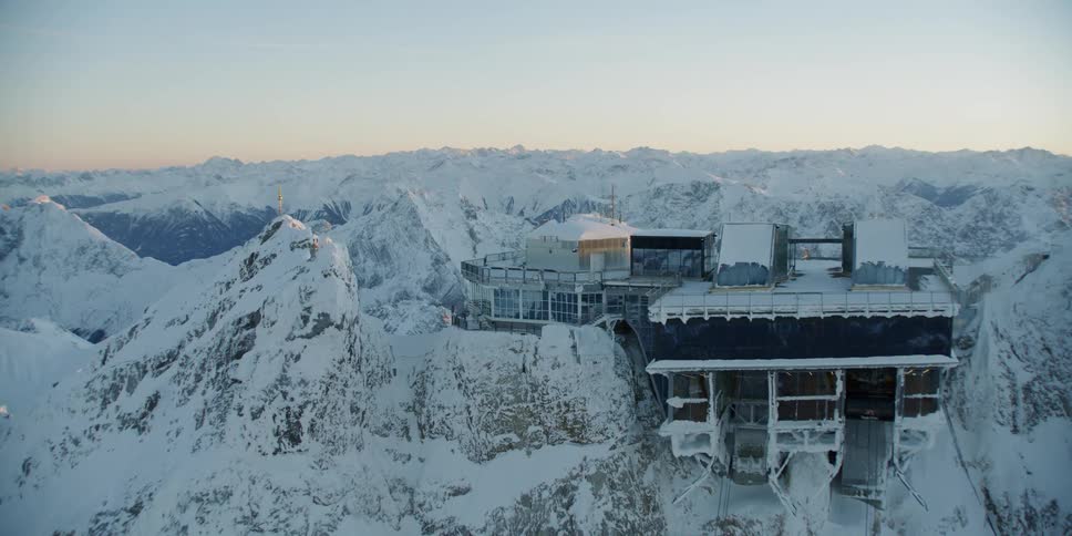 A large building sits atop a snowy mountain