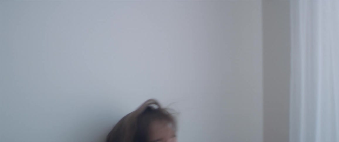 A woman smiles and dances against wall