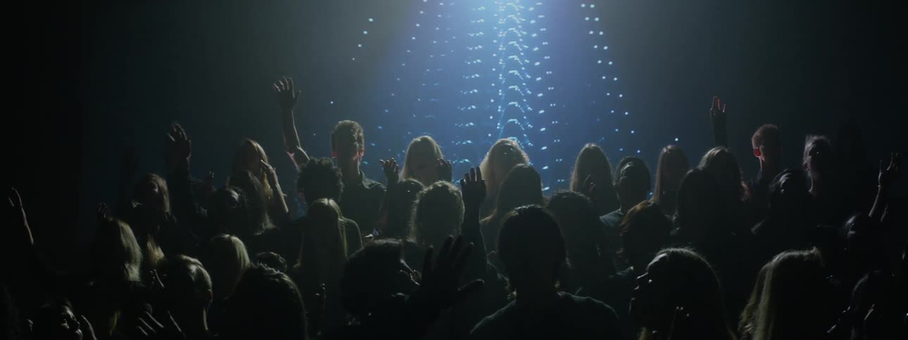 Members of a choir are raising their hands as they sing on a stage