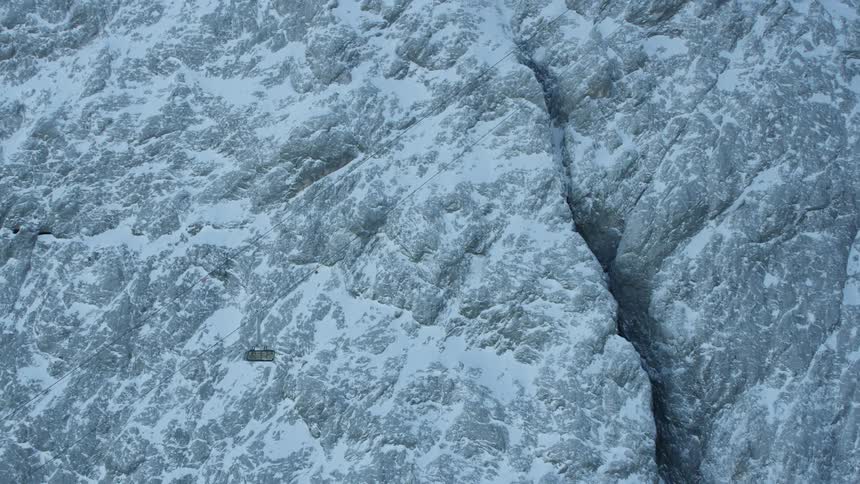 A gondola moves up a snowy mountainside