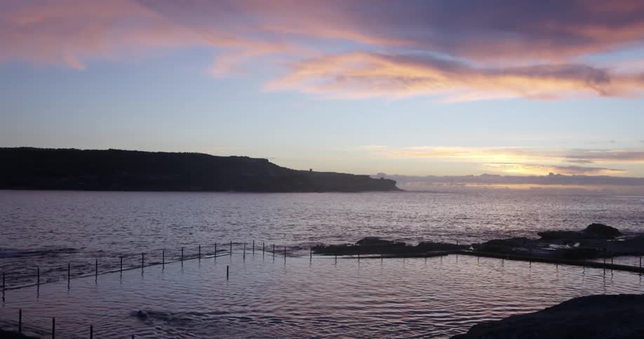 Hills can be seen in the distance across water at sunset