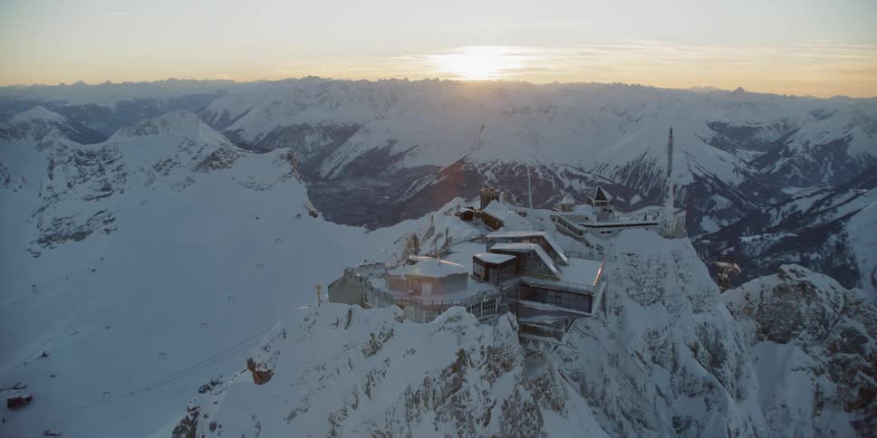 There is a building on the top of the snow covered mountain