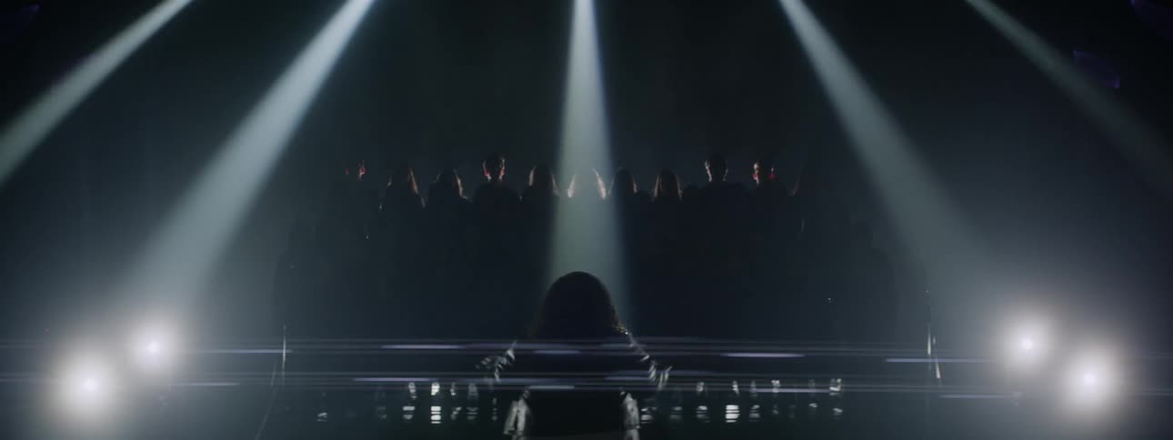 Woman is orchestrating a choir in dark room