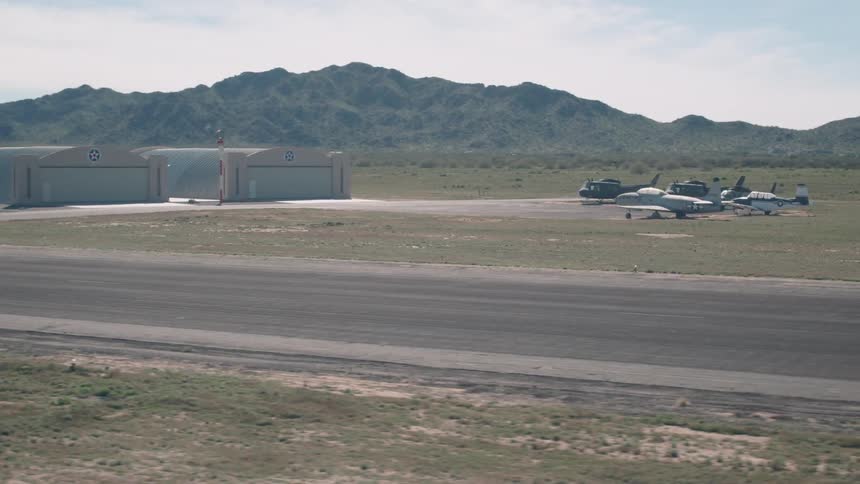 Airplanes and helicopters are parked at a rural airport