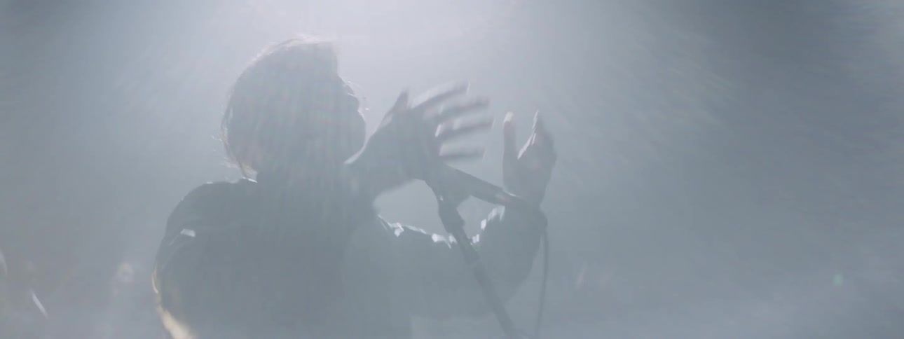 A woman raises her hands singing into a microphone